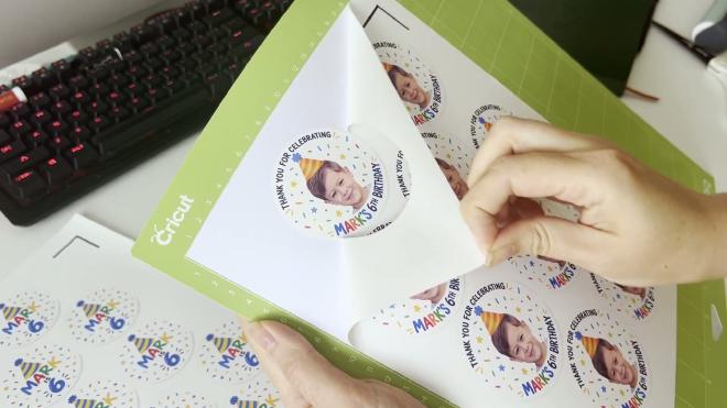 Peeling a round Mark&rsquo;s 6th birthday sticker off the backing on a Cricut mat