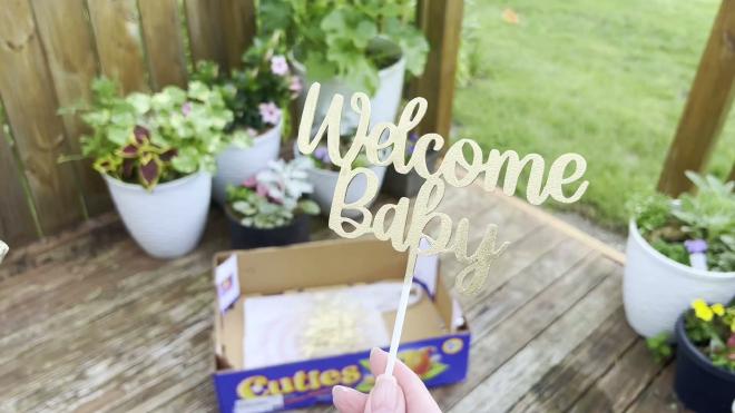 Finished gold Welcome Baby cake topper after spray painting