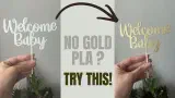 White 3D printed Welcome Baby cake topper transformed into a gold metallic cake topper