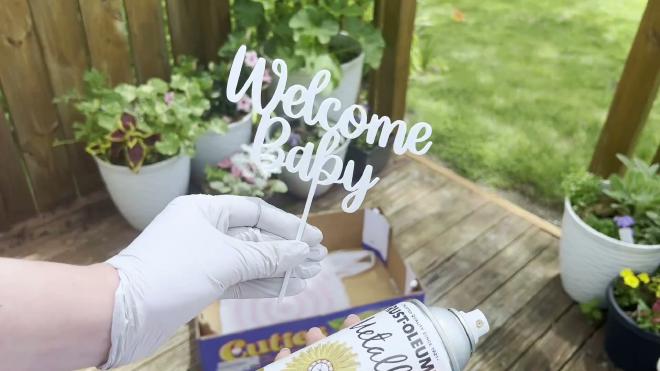 White PLA Welcome Baby topper held outside before spray painting