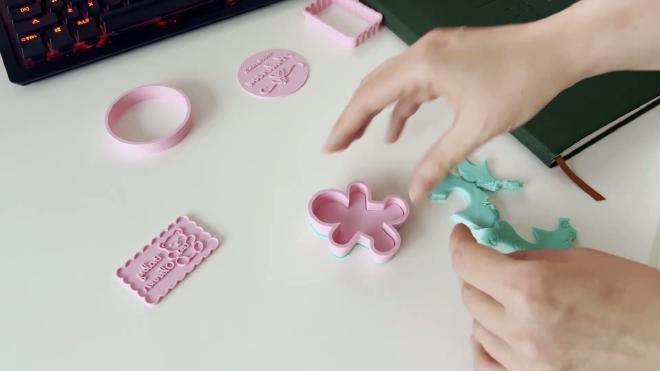 Using a pink gingerbread cookie cutter to cut a personalized fondant shape